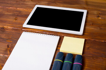 A white tablet and stationery on a dark wooden table.