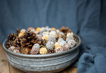 Weihnachten Dekoration – Metallschale mit verschiedenen Zapfen auf hölzernen Hintergrund 