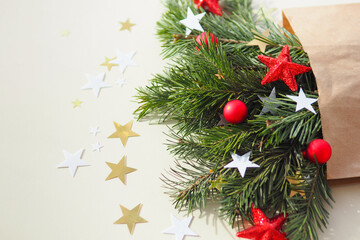 craft package and fir branches with red, gold and white stars and Christmas balls on a beige background..