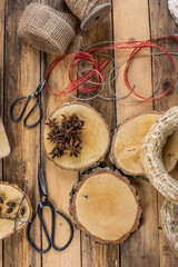 Holzscheiben auf rustikalem hölzernem Untergrund mit weihnachtlichen Accessoires, Geschenkband und Anis 