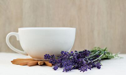 Cup of healthy hot lavender tea and lavender bouquet on a wooden table. Concept of a healthy lifestyle.