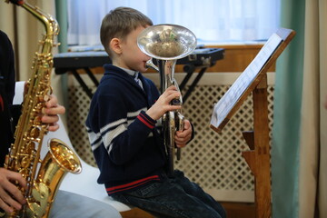 Elementary school student playing a musical instrument tuba on notes in an orchestra.Background...