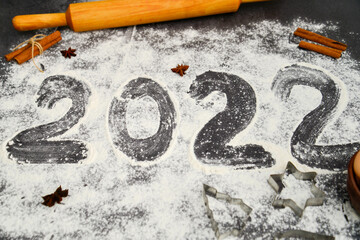 The writiing of 2022 made of flour. new year. dark background. flatlay.