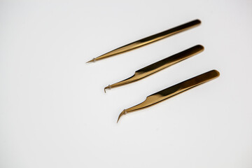 tools for eyelash extensions and eyebrow design. cosmetic tweezers in gold color on a white background