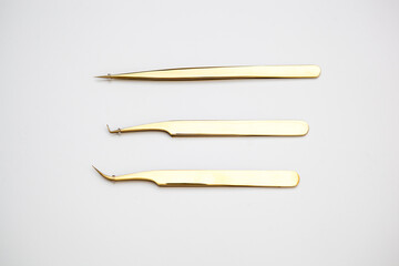 tools for eyelash extensions and eyebrow design. cosmetic tweezers in gold color on a white background