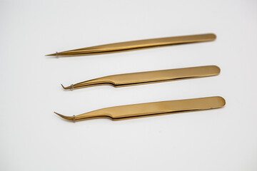 tools for eyelash extensions and eyebrow design. cosmetic tweezers in gold color on a white background
