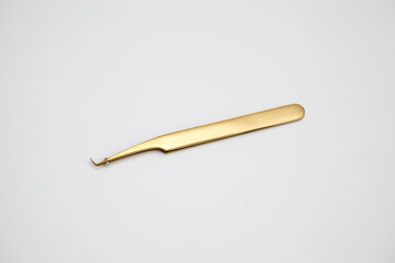 tools for eyelash extensions and eyebrow design. cosmetic tweezers in gold color on a white...