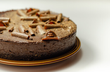 Digestive biscuit base with chocolate cheesecake and pockets of salted caramel sauce, topped with chocolate ganache, milk chocolate curls, and gold shimmer