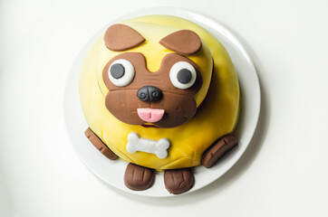 Pug dog cake, sponge with a frosting and raspberry jam filling, covered and decorated with soft icing and edible decorations