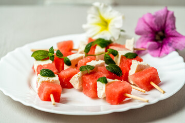 watermelon canapes with cheese sprinkled with mint on a plate