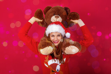 pretty woman with santa hat, reindeer sweater and giant teddy bear on her shoulders.