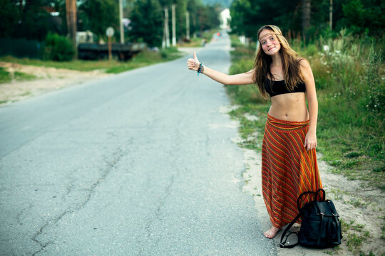 A hippie girl voting near the rural road. Hitchhiking trips.