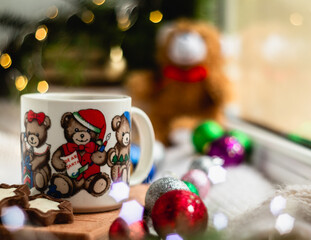 Christmas still life with a cup of hot tea with the image of bears on a blurred shiny background. Christmas concept.