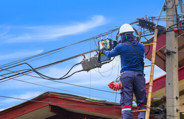 Technician on wooden ladder using smartphone to record screen image of internet signal tester instrument after network connection is completely.