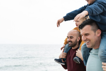 Gay fathers and children playing outdoor on the beach - LGBT family love concept - Soft focus on...