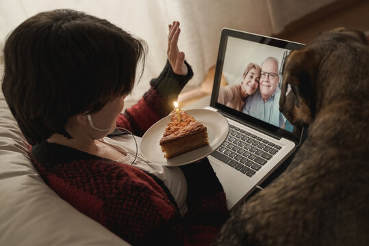 Happy daughter and senior parents doing video call birthday party at home with pet dog - Family, remote meeting concept