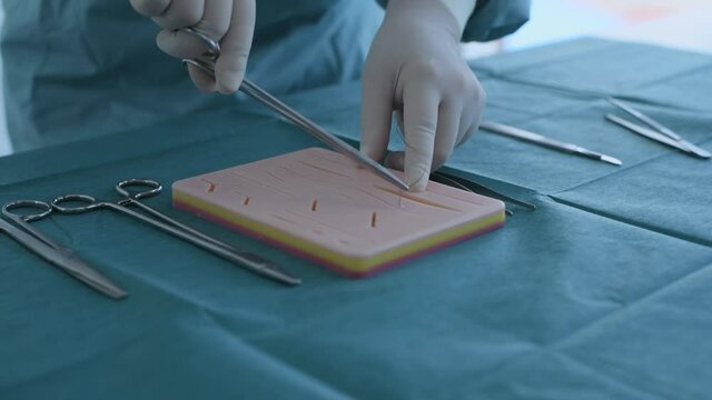Education concept of 4k Resolution. A doctor is practicing sutures with a practice apparatus.