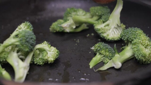 mixing broccoli with wood spoon on oil fry pan slow motion
