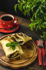 Breakfast with sweet chocolate sandwich-sized calzone  and coffee served on dark wooden table.