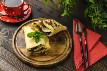 Breakfast with sweet chocolate sandwich-sized calzone  and coffee served on dark wooden table.
