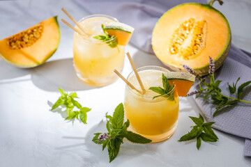 Melon juice, lemonade in glasses with ice and melon slices garnished with basil leaves