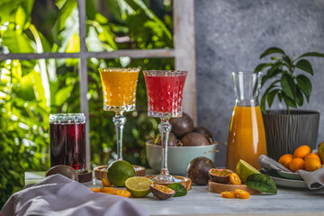 Two elegant glasses of mango, kumquat and passiflora liqueur on light gray table surface near...