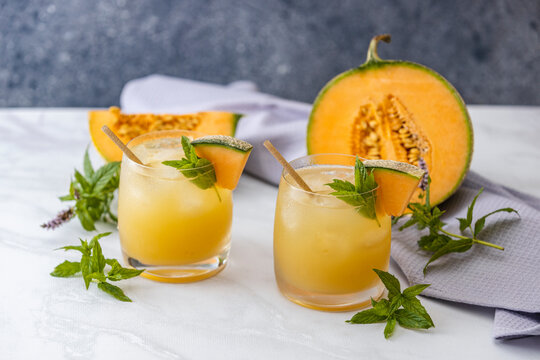 Melon juice, lemonade in glasses with ice and melon slices garnished with basil leaves