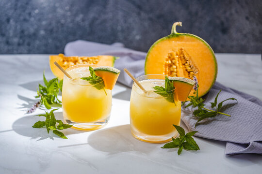 Melon juice, lemonade in glasses with ice and melon slices garnished with basil leaves