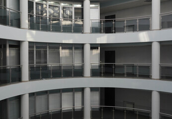 Photo in a building of several gray floors with glass balconies and white columns