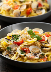 White shell clams in Garlic and parsley white wine sauce tagliatelle pasta served with cherry tomatoes and parmesan cheese