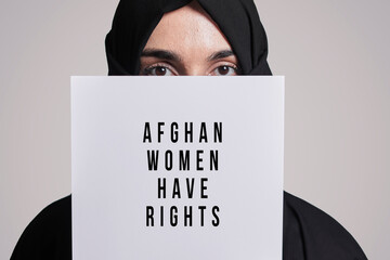 Muslim woman holding a paper with text - Afghan women have rights. Muslim woman in traditional...