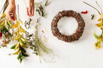 Flat lay with diy floral autumn wreath with driad grass, plant and berry