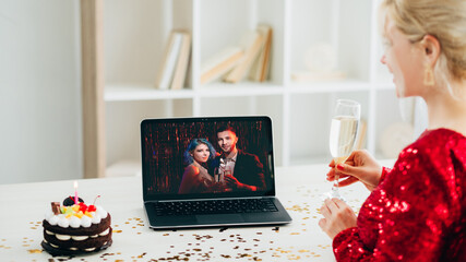 Virtual party. Christmas greeting. Online connection. Festive woman with glass champagne holiday cake getting congrats from couple on laptop in light home interior.