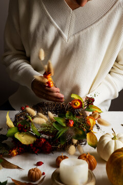 Woman hands with diy floral autumn wreath with driad grass, plant and berry