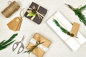 Christmas gifts wrapped in craft recycled paper on linen background. Nature aesthetic. Winter holiday celebration