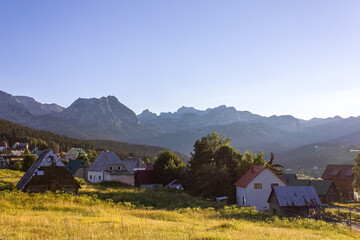 Mountain landscape: a view of the village and mountain peaks, illuminated by the soft and warm light of the setting sun