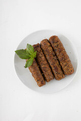 Vegan seitan kebab with basil on a white plate. White background, top view.