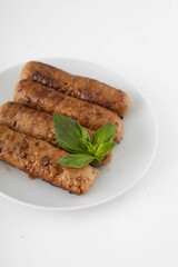 Vegan seitan kebab with basil on a white plate. White background, close view.