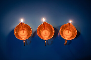 Happy Diwali. Diya on blue background. Traditional oil lamp. Celebrating festival of light.