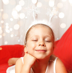 A cute little girl smiles and dreams of a miracle for Christmas. New year concept. 2021. Happy...