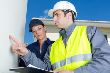 male and female plasterer in uniform polishing the wall