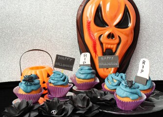 Halloween pastry: cupcakes with decoration of "happy Halloween", RIP tombstones, insects, pumpkins flowers with skulls