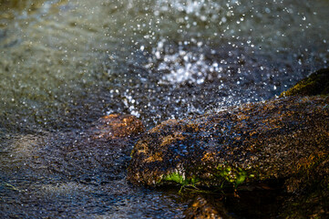 close-up view of water splashing over a rock in a pool under a fountain