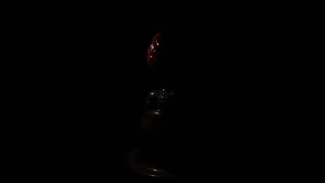 Abstract piece of art isolated on a black background under the spotlight changed by shadow. Design. Red gemstone egg at the exhibition.