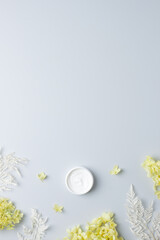 Jar of cosmetic cream with flowers on grey background. Flat lay, copy space