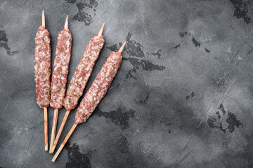 Raw mutton kebab shish skewers, on gray stone table background, top view flat lay, with copy space for text