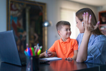 Mother explain to happy son at laptop in home office