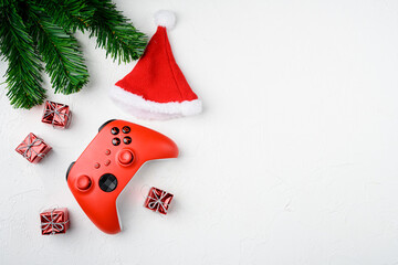 Red gamepad among Christmas tree toys, on white stone table background, top view flat lay, with...