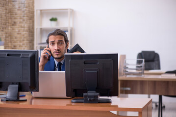 Young male employee in multitasking concept