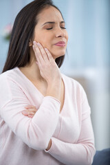 woman with sensitive teeth and apple on sofa at home